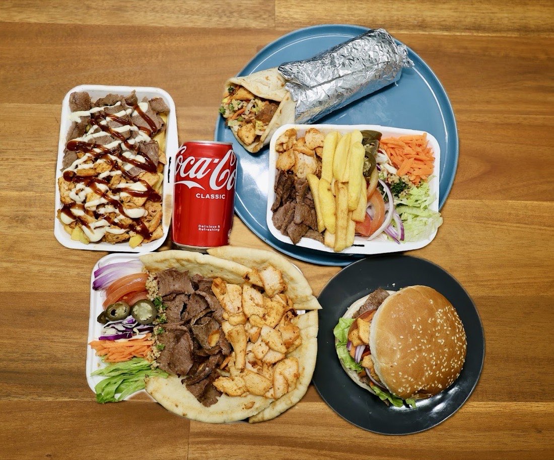 A spread of wraps, loaded chips, a burger and a cold drink from Wainoni Kebab & Grill Center